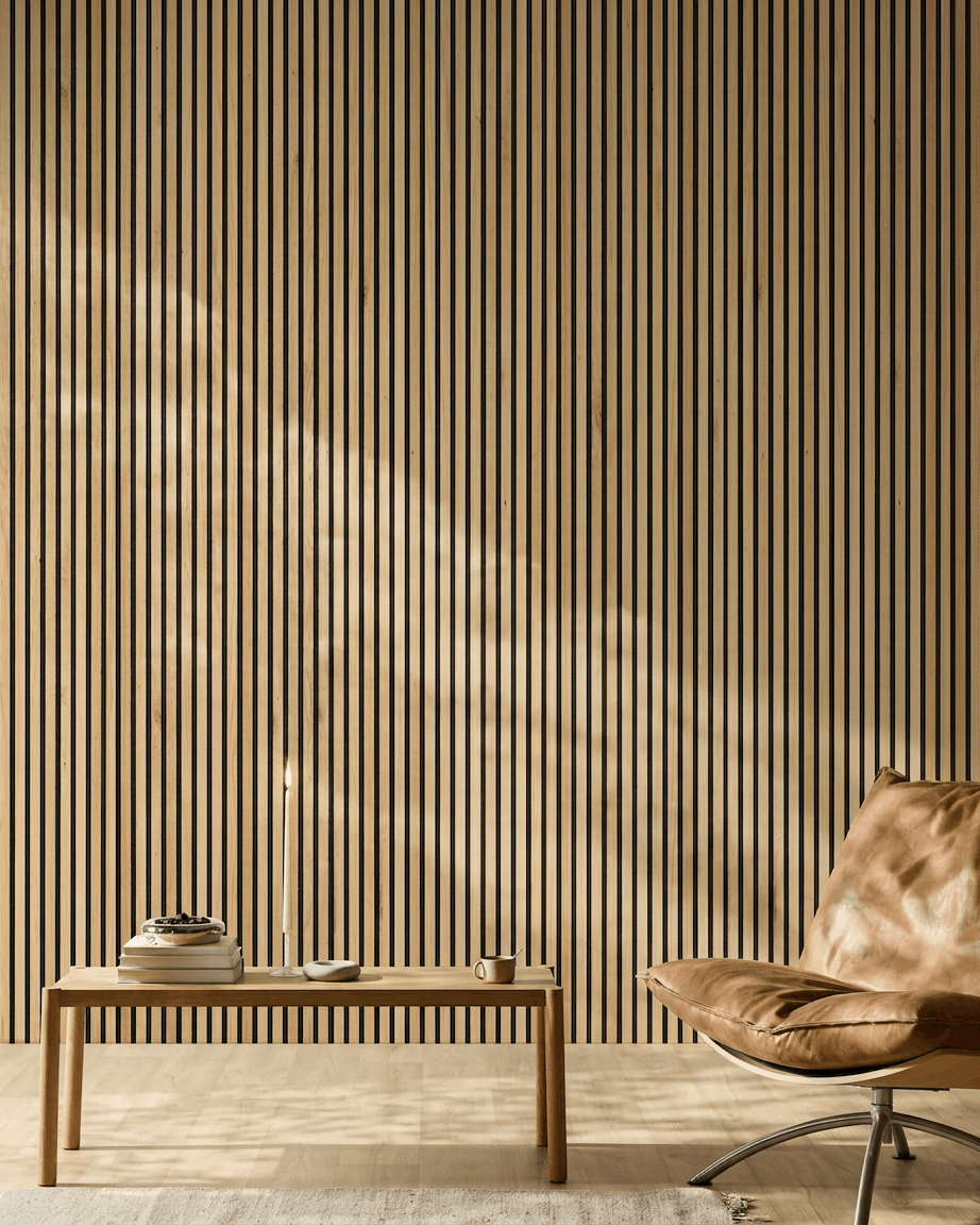 A luz do sol ilumina uma divisão moderna com um Akupanel Painel acústico da WoodUpp em Rustic Natural Oak na parede, a par de uma cadeira em pele castanha e de um banco minimalista.
