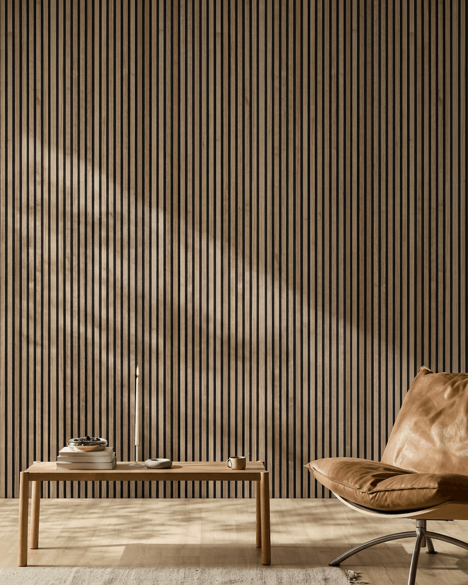 Divisão nórdica minimalista com painel acústico de madeira WoodUpp Akupanel em nogueira, cadeira em pele bege e mesa de centro em madeira com livros e uma vela.