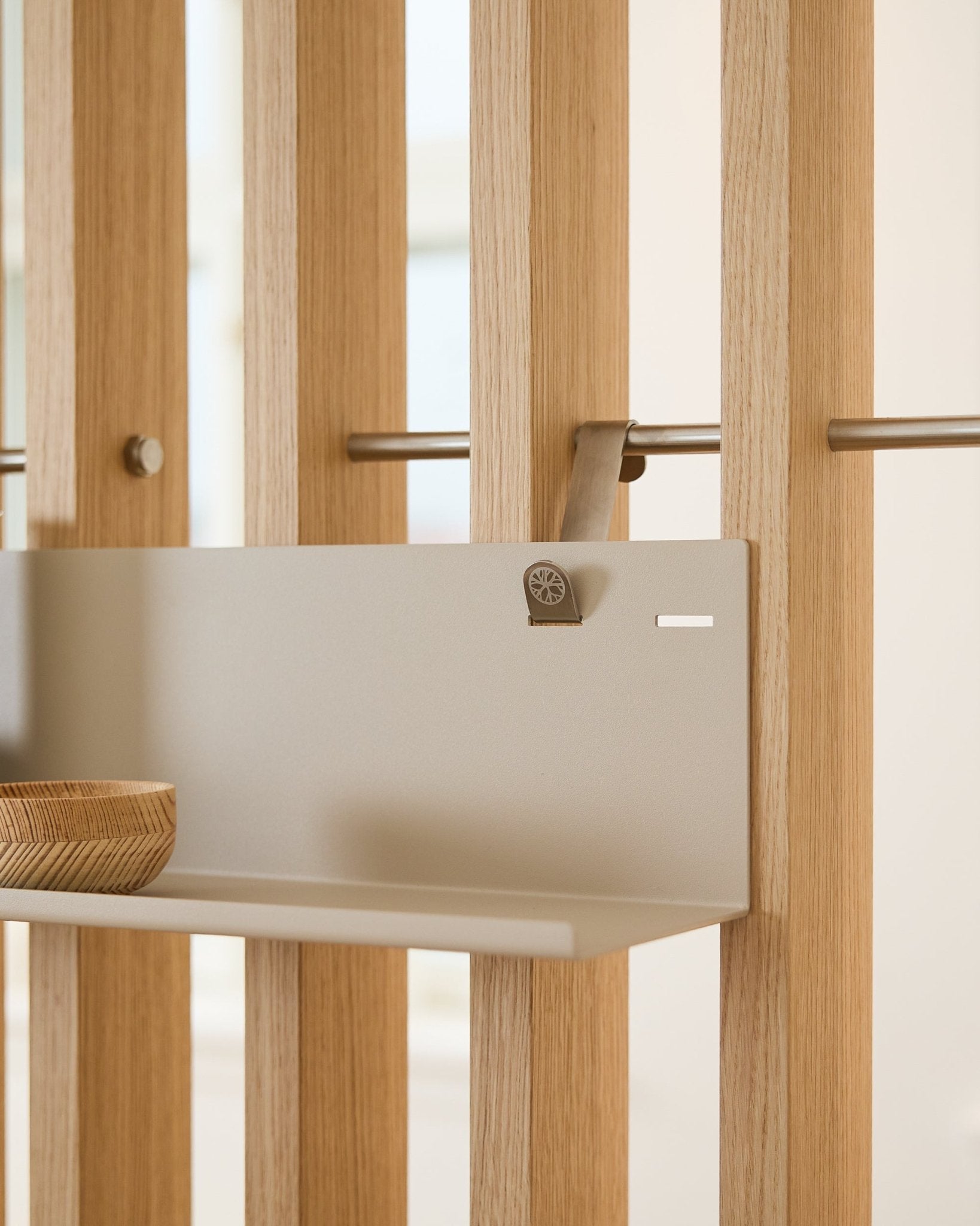 Prateleira metálica WoodUpp BM1 Beige (63 x 13,4 cm) montada num painel acústico ripado vertical, com uma taça de madeira no lado esquerdo da prateleira.