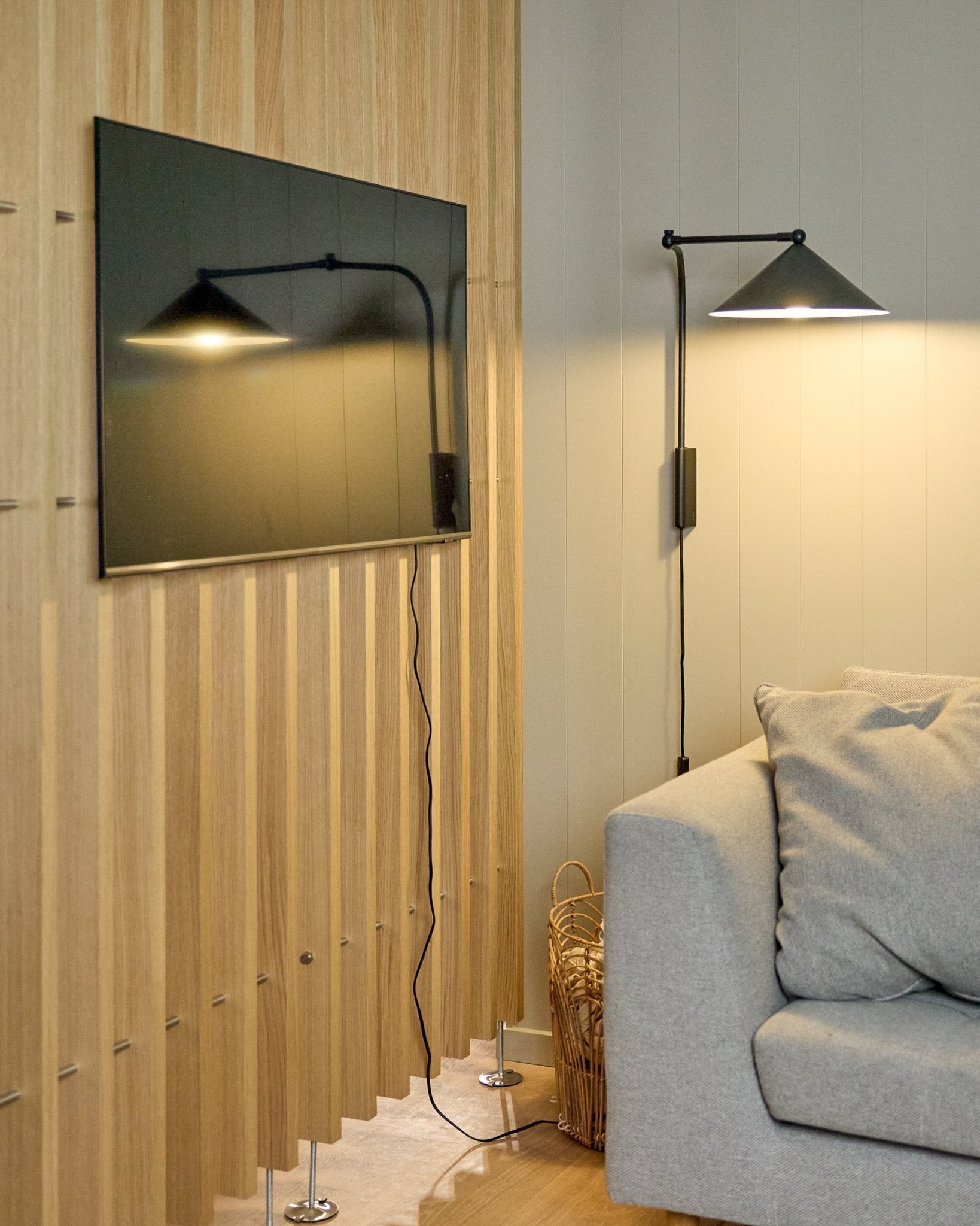 O Nell | TV-Mount / BM1 da WoodUpp (Beige, 64x44 cm) fixa uma TV de ecrã plano num Painel acústico nórdico ao lado de um sofá cinzento; cesto nas proximidades.