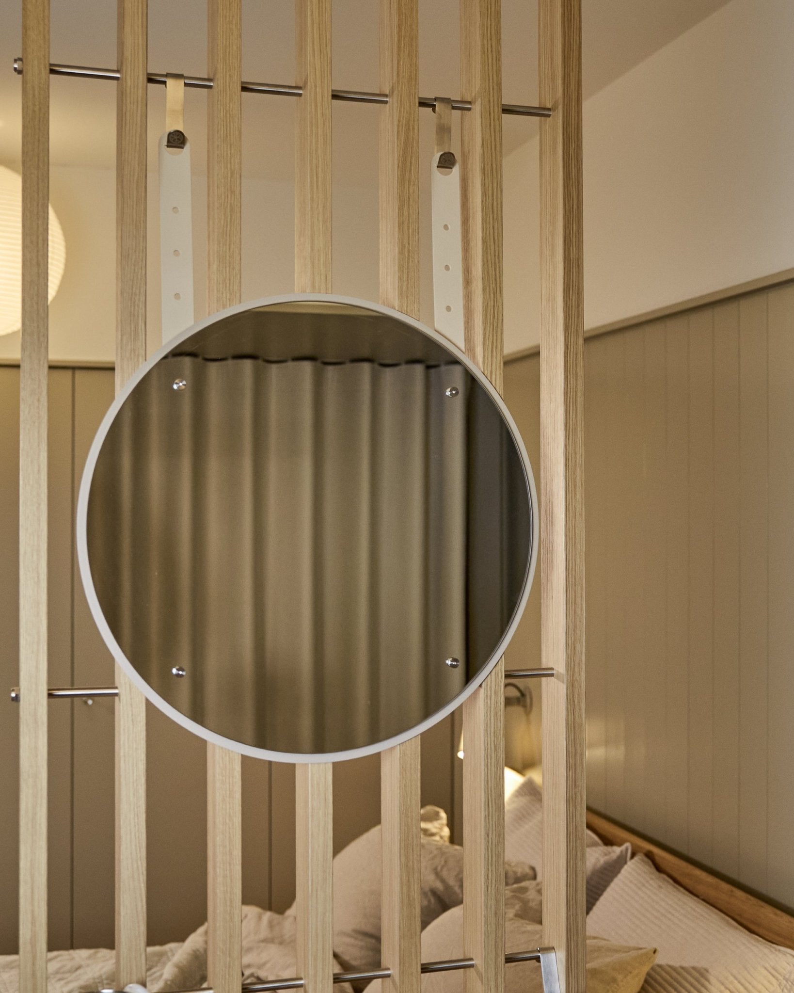 Espelho redondo Vala BM1 da WoodUpp, com altura regulável e 54 cm de diâmetro, montado num painel acústico ripado em madeira vertical, com uma iluminação suave em tons neutros.