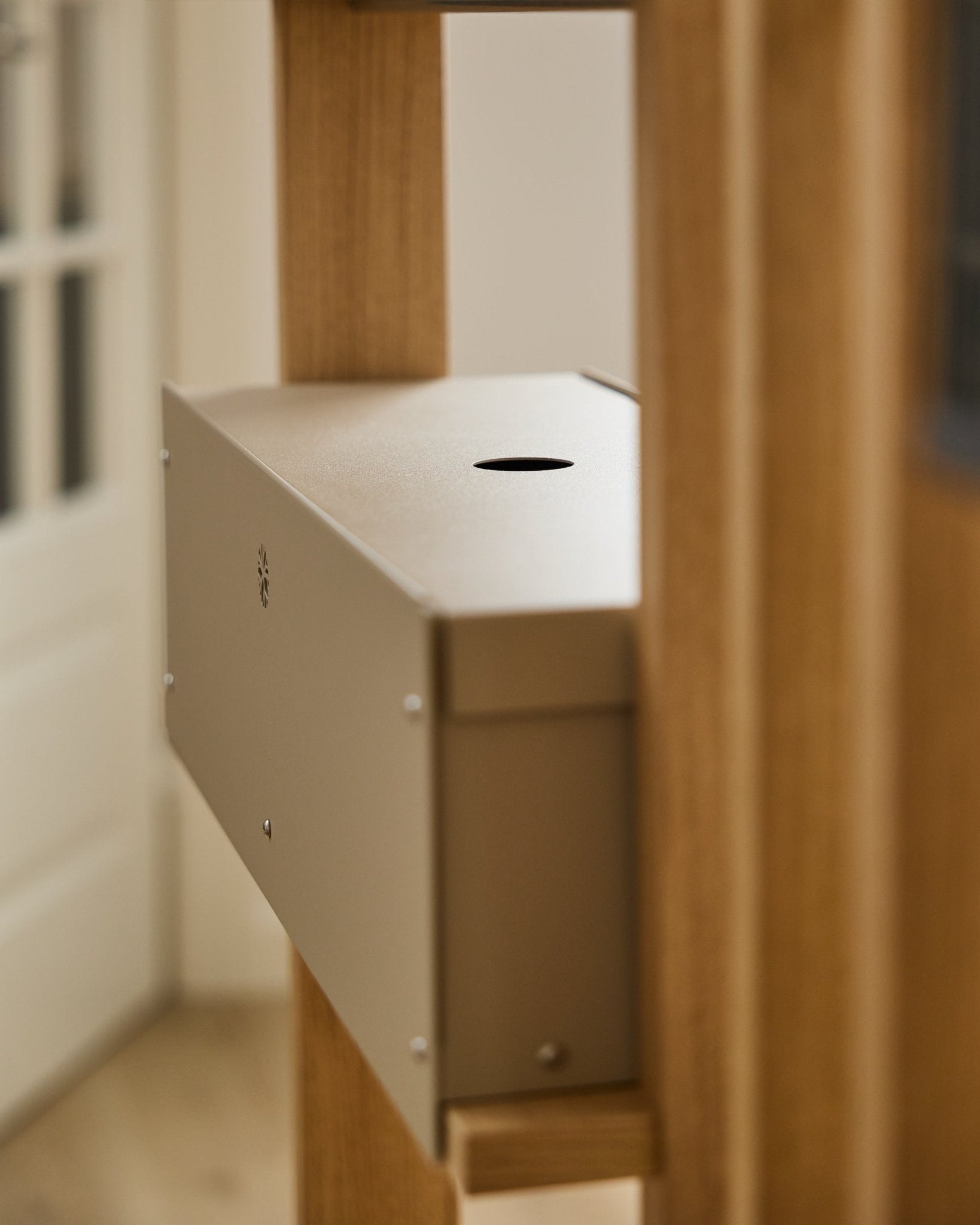 O Nell | Metal Box / BM2, Beige da WoodUpp é um acessório em steel com revestimento a pó da coleção CREATE, colocado entre painéis acústicos de madeira junto a uma porta branca.