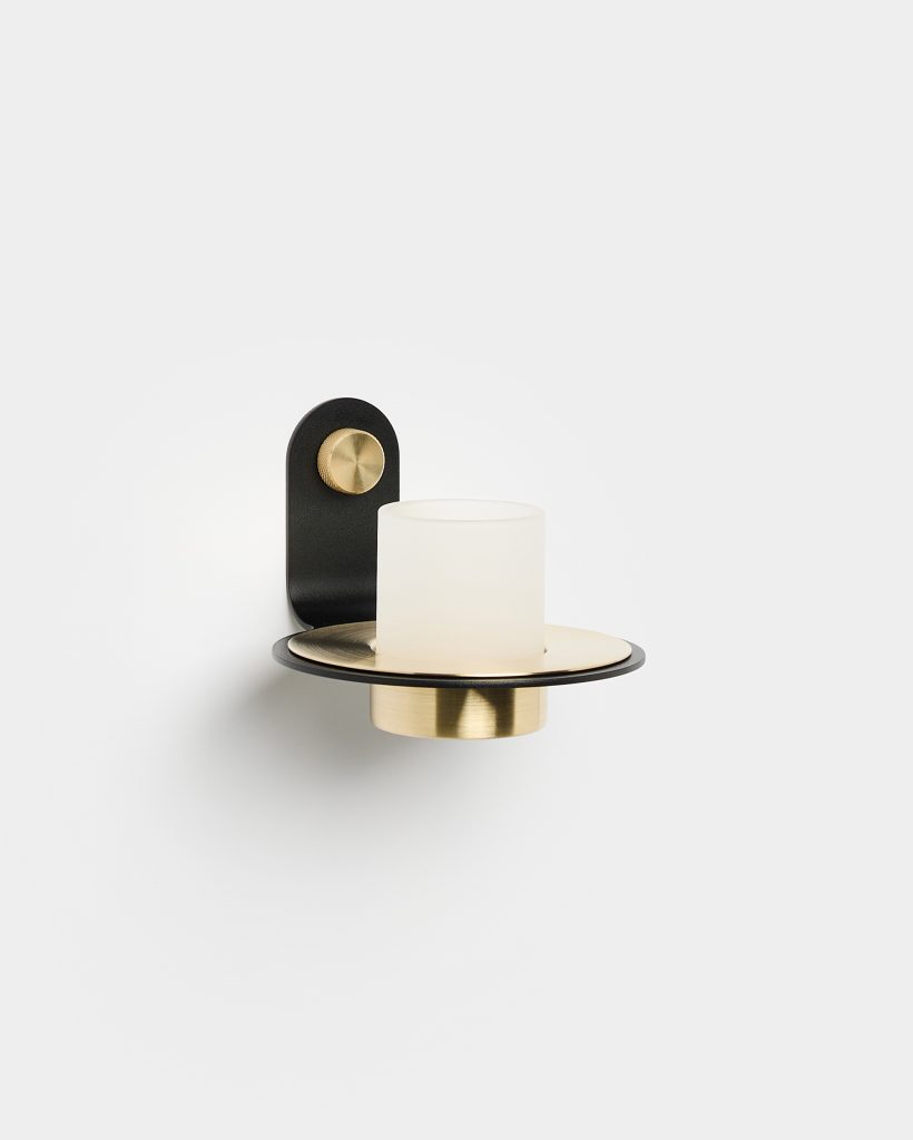 Arandela WoodUpp fixada numa parede branca: suporte em metal preto com botão dourado, prato circular em latão acetinado e difusor cilíndrico de vidro opalino que suaviza a luz, base metálica dourada e montagem discreta, criando um candeeiro de parede elegante e minimalista.