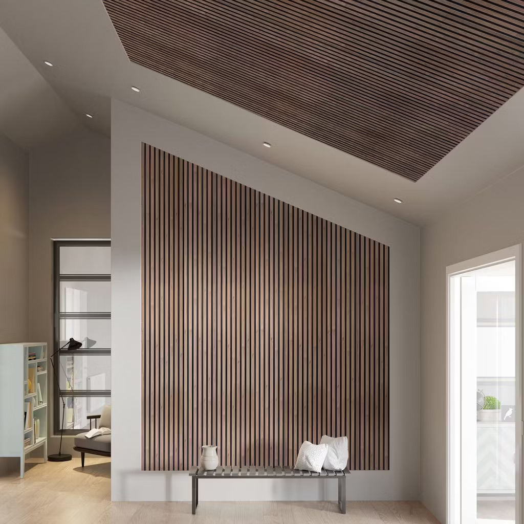 Interior minimalista com painel ripado vertical WoodUpp cobrindo parede inclinada e painel ripado WoodUpp no teto; ripas de madeira escura com espaços pretos; banco baixo metálico com almofadas e vaso no chão, janelas e estante ao fundo, com iluminação embutida e tons neutros.